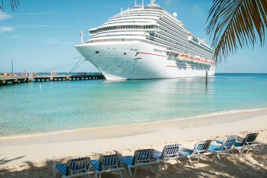 A majestic cruise ship docked at a sunny beach.