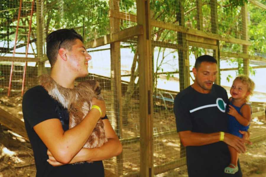 A family enjoying a close-up moment with a sloth, capturing a heartwarming interaction in nature.