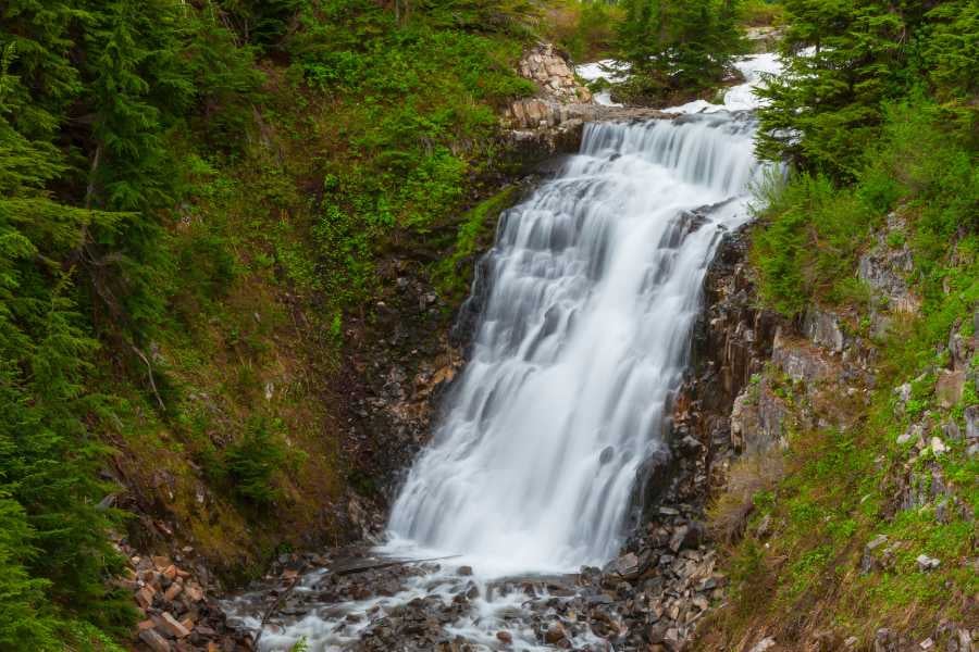 Cascading waterfall flows through lush greenery and rocky terrain.