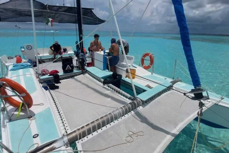 A relaxed catamaran trip with guests lounging on netted decks, surrounded by pristine turquoise waters.