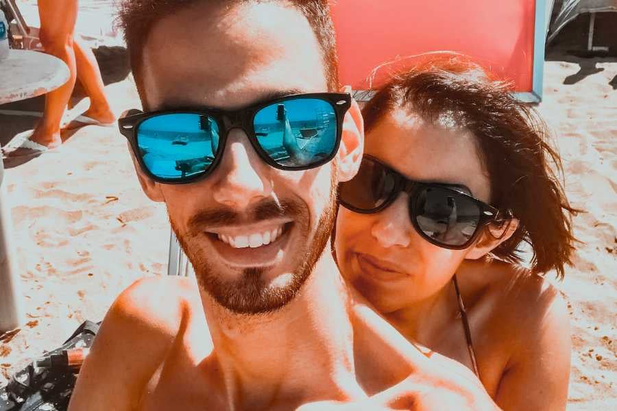 A happy couple enjoying sunny beach vibes with stylish sunglasses.