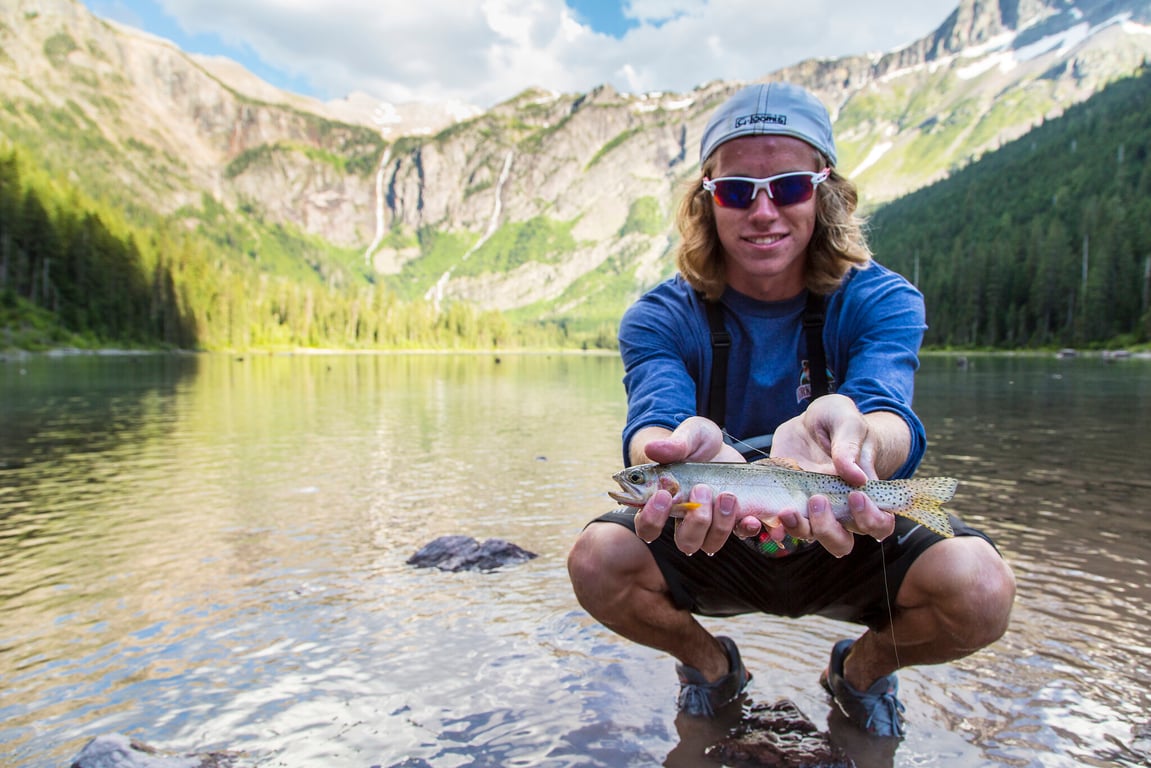 young man holding fish at avalanche lake