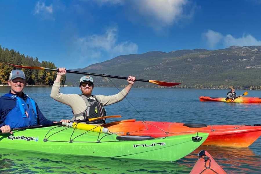 Two friends kayaking on a peaceful lake, enjoying the sunshine and fresh mountain air.