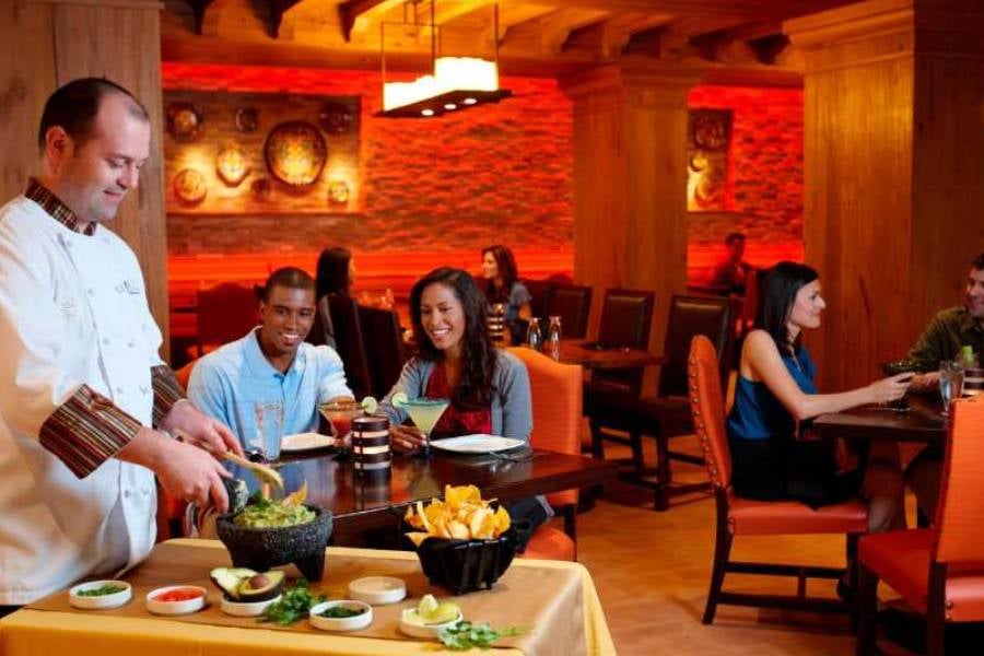 A chef makes guacamole at your table while guests enjoy drinks and dinner.
