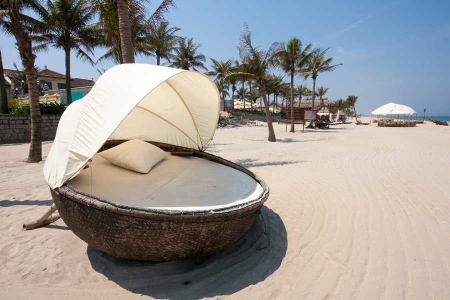 A cozy, shaded lounge bed nestled on a pristine beach, ideal for sunbathing or an afternoon nap.