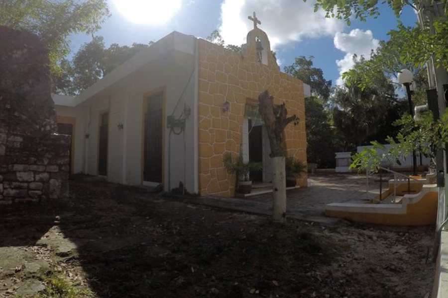 A charming yellow chapel with a rustic design, nestled among trees, offering a peaceful and spiritual atmosphere.