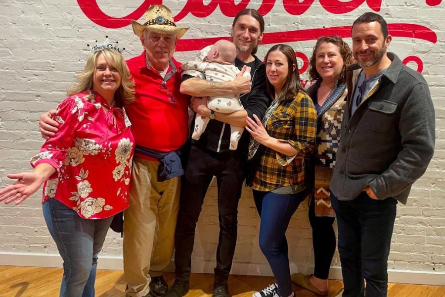 A cheerful family celebrates together under a bold red sign.