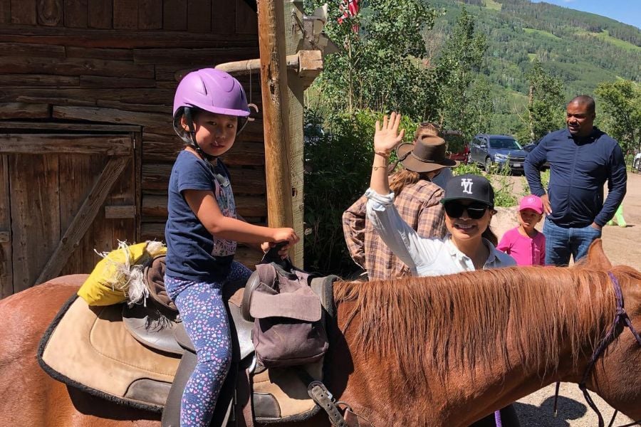 A young rider waves happily while exploring Vail on horseback.