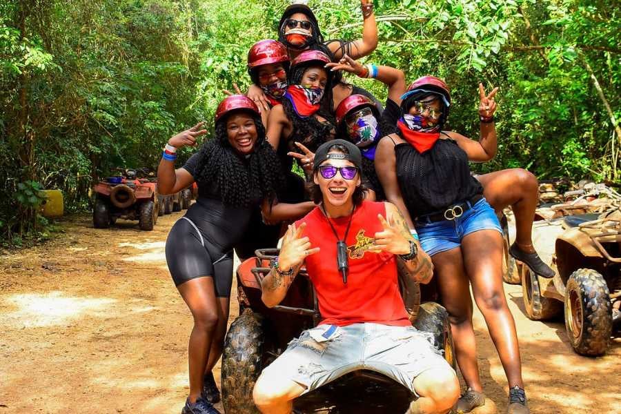 A group of people smiling and posing for a photo after an ATV adventure in the jungle.