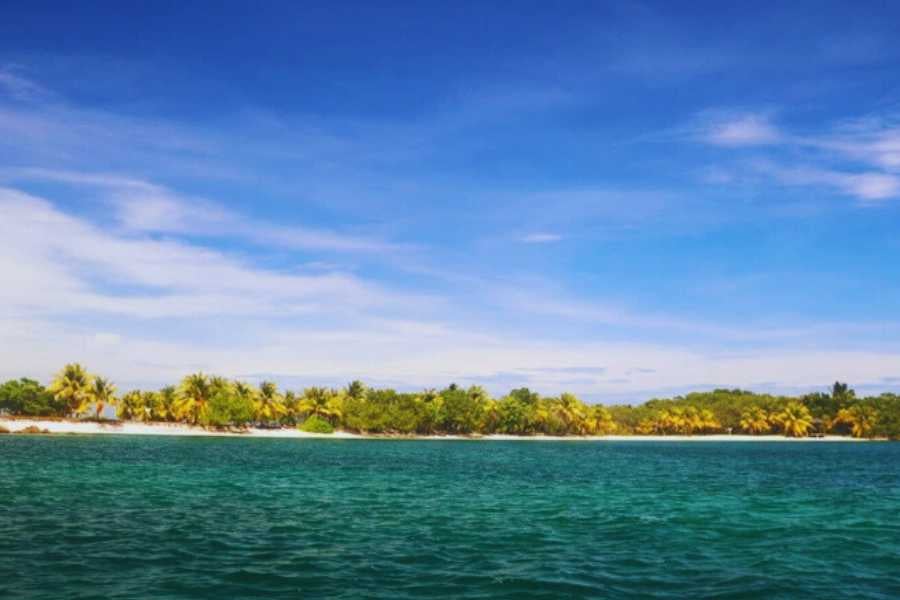 A peaceful beach scene with clear waters and a stunning sky in the distance.