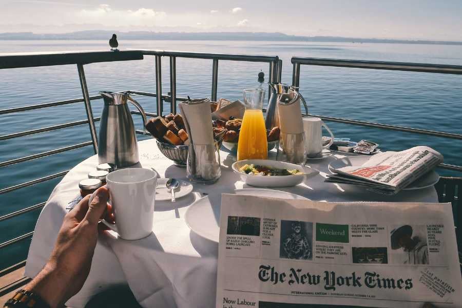 A peaceful breakfast scene on a cruise ship deck, with coffee, orange juice, and pastries overlooking the ocean.