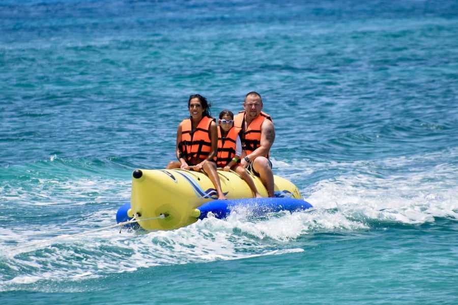 A family rides a bright yellow banana boat over the ocean, wearing life jackets and enjoying the thrilling waves.