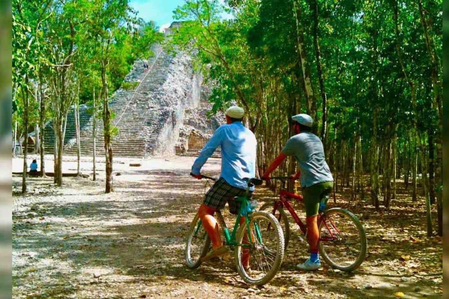 Cyclists pause near an ancient pyramid, enjoying the scenic jungle view and cultural history of the site.