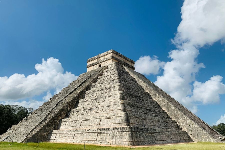 A towering Mayan pyramid rises toward the sky with steep stone steps.