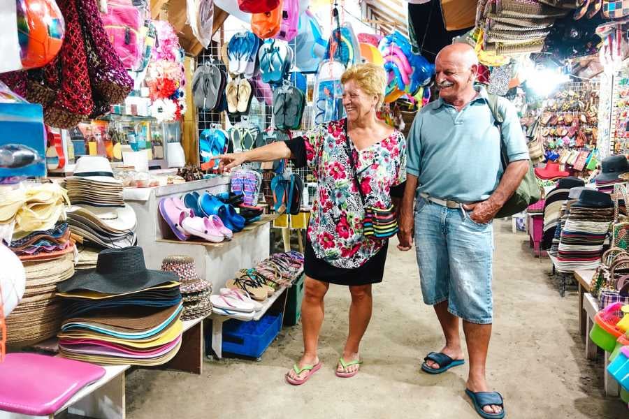 A bustling market filled with colorful hats, sandals, and souvenirs, with a happy couple shopping.