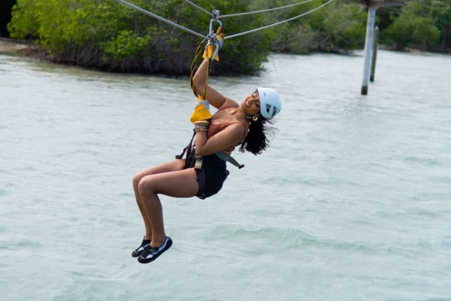 A woman glides effortlessly over the water on a zip line, embracing an exhilarating adventure in a breathtaking setting.