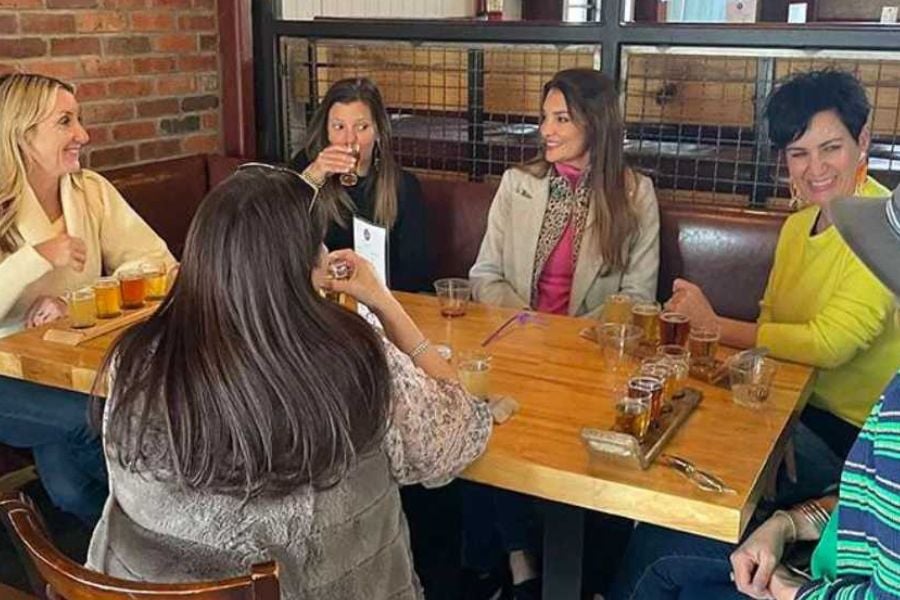 Friends laugh and sip drinks during a fun outing at a cozy brewery.