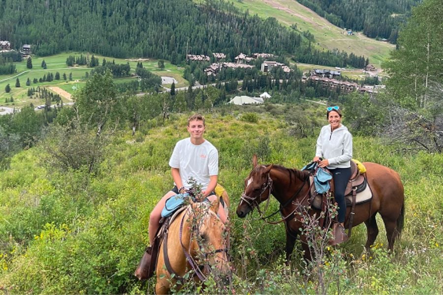 A mother and son enjoy horseback riding with beautiful Breckenridge mountain views.