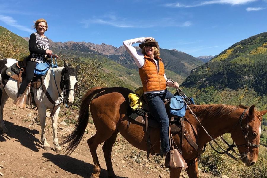 Two women smile while riding Vail’s breathtaking alpine trails.