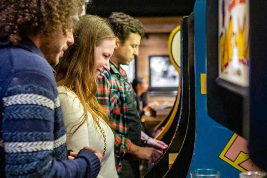 Friends enjoy playing old-school arcade games together.