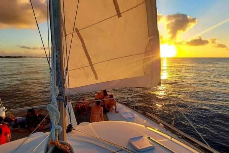 A catamaran sails into a breathtaking sunset, as passengers soak in the golden hues over the ocean.