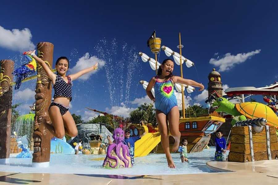 Two kids joyfully jump through a colorful water park, surrounded by pirate ships and playful sea creatures.