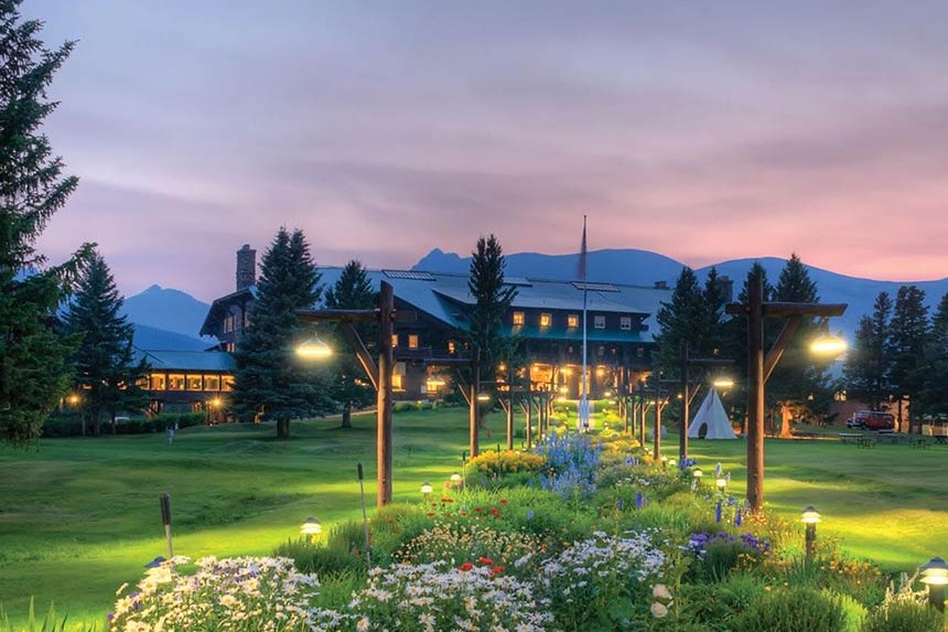 flowers in foreground with brown lodge and sunset behind