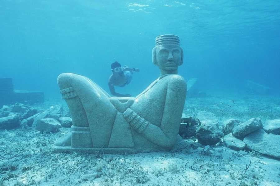 A stunning submerged statue with a snorkeler exploring the crystal-clear waters around it.