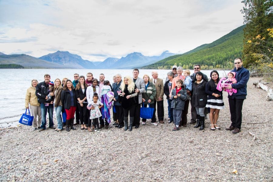 A group gathers by a peaceful mountain lake for a photo.