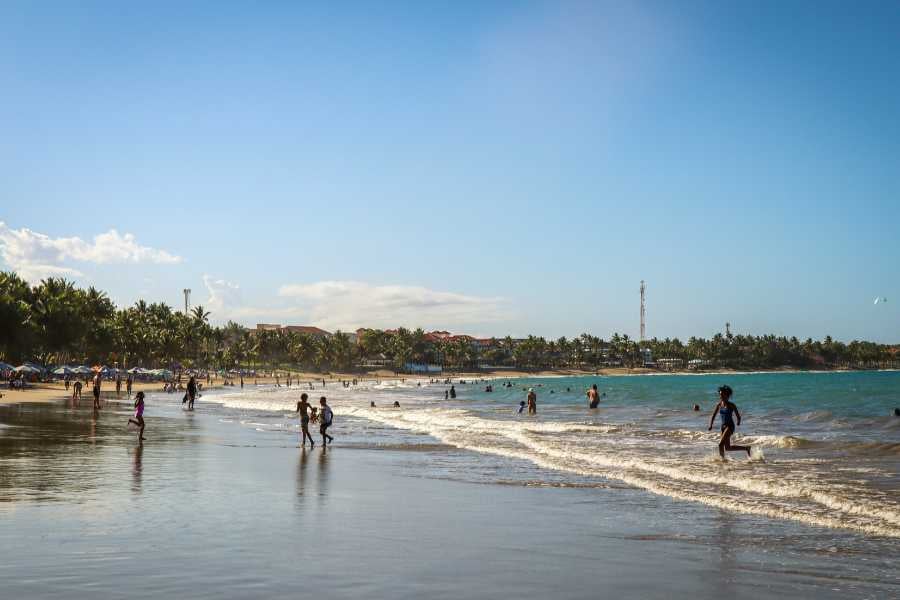 People stroll along the beach, enjoying the sun and sea, with a mix of activity and relaxation.