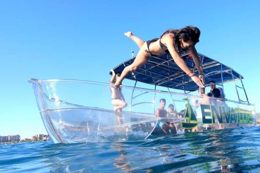 A woman taking a leap into the water from a clear-bottom boat, ready for an adventure.