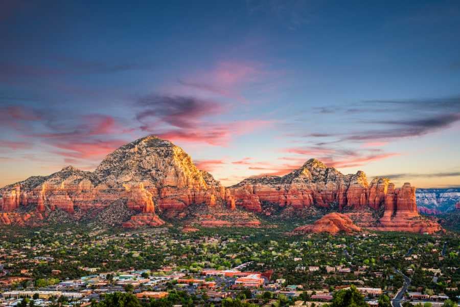 A wide view of Sedona’s red rock mountains glowing at sunset.