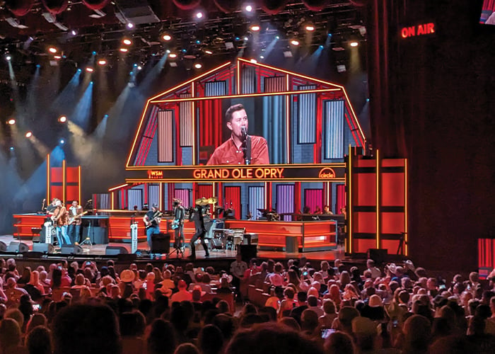 Friends sit under glowing lights, watching a live show at the Grand Ole Opry.