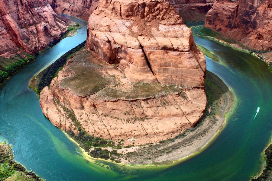 A huge red rock is surrounded by a river making a perfect horseshoe shape.