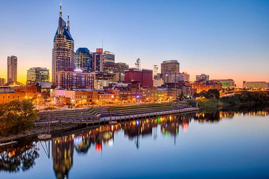 Downtown skyline lights reflect on the river at sunset.