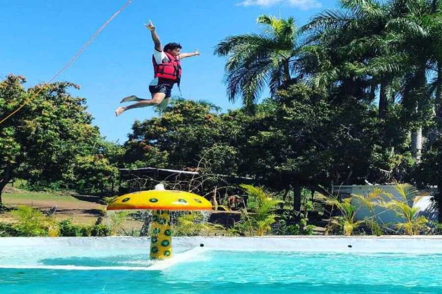 A person enjoying an exciting water activity, soaring through the air over a pool.