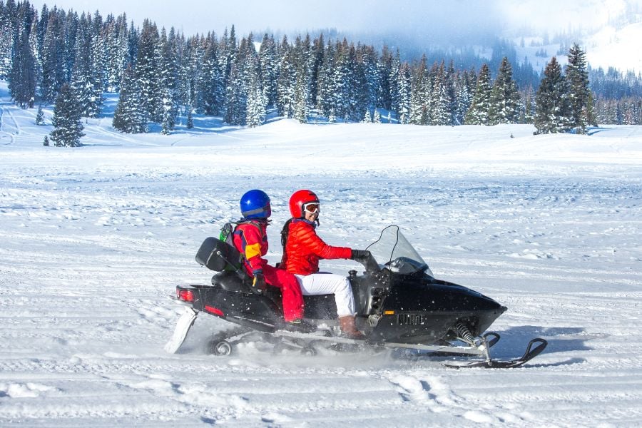 Two riders explore snowy meadows by snowmobile in Vail.