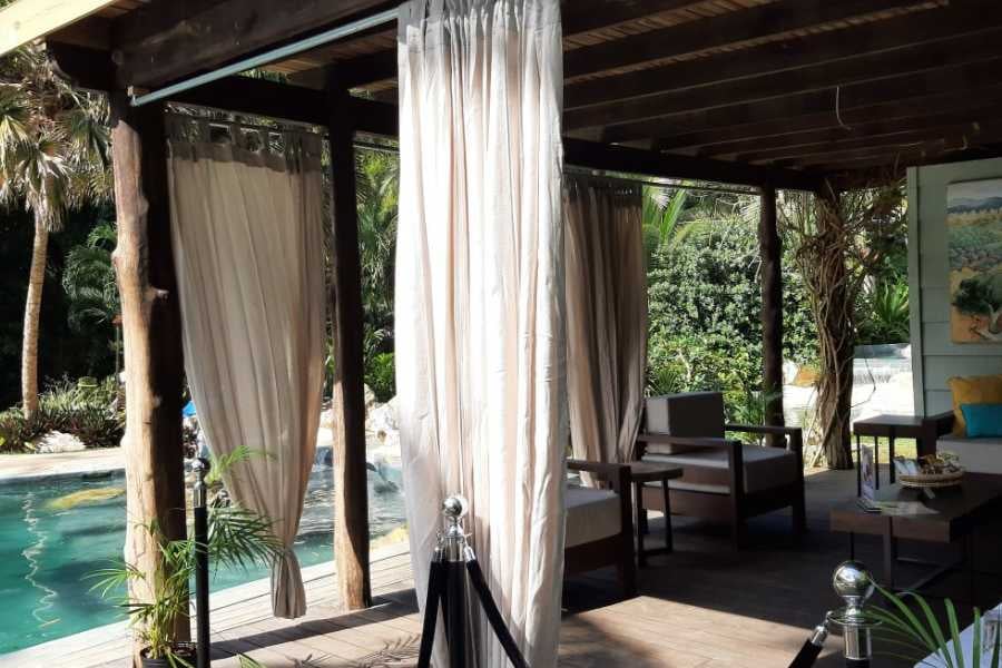 A cozy outdoor spa with elegant curtains, comfortable seating, and a lush tropical atmosphere.