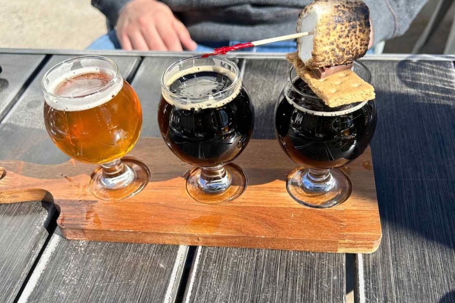 A creative beer flight with one topped by a toasted marshmallow treat.