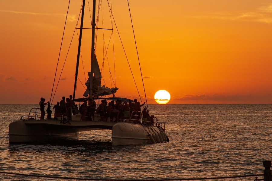 A group of people sailing at sunset on a beautiful, serene catamaran ride.