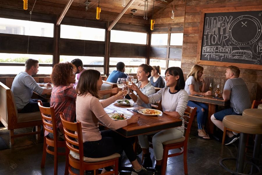 Groups share meals and toast drinks in a cozy wooden restaurant.