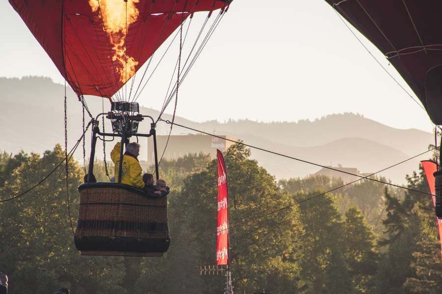 A hot air balloon lifts off as flames shoot up to fill it with heat.