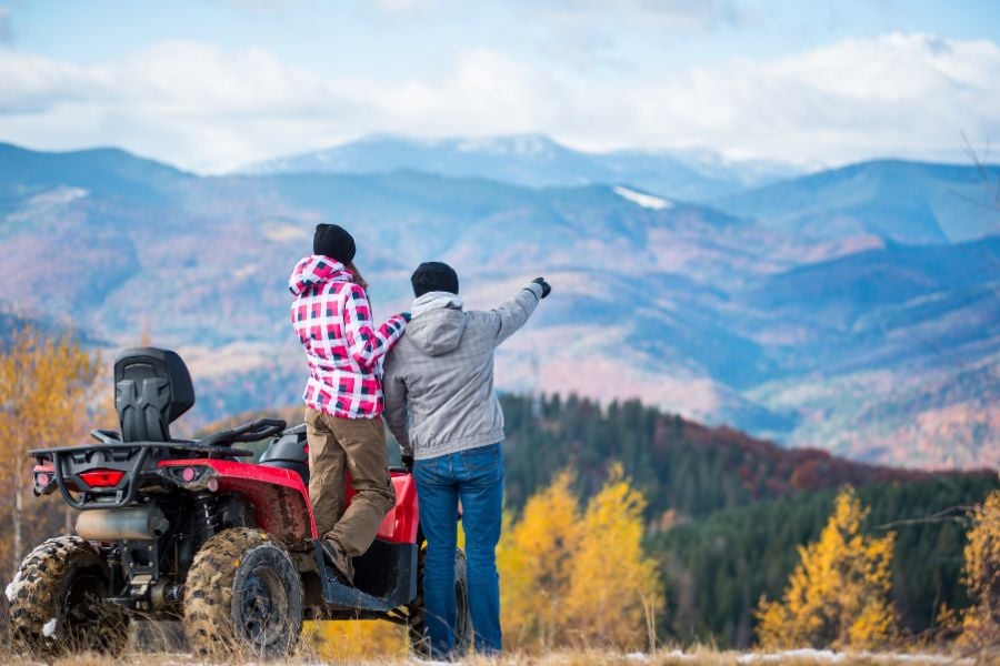 Couple enjoying stunning autumn mountain scenery near their ATV in Vail, Colorado.