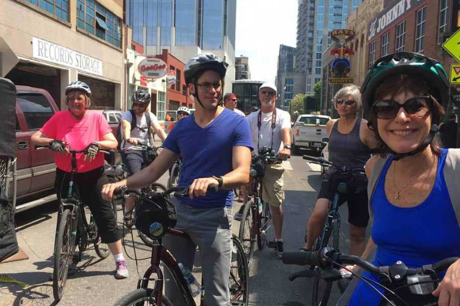 A group of people on bikes explores the city on a sunny day.