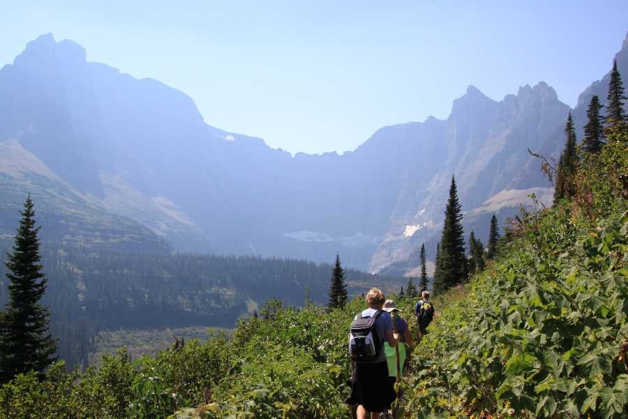 A group of hikers traverses a scenic mountain trail with panoramic views.