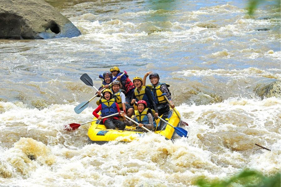 Team braves swirling brown rapids, laughing through the wild ride.