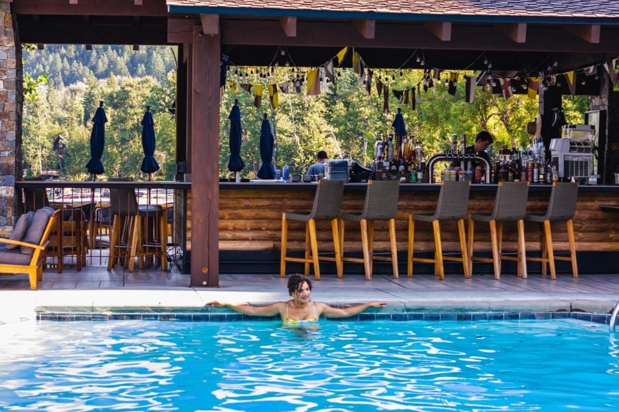 Woman unwinds in the pool near a lively outdoor bar.