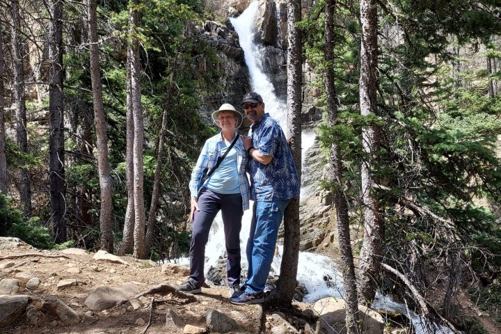 couple in woods with waterfall behind