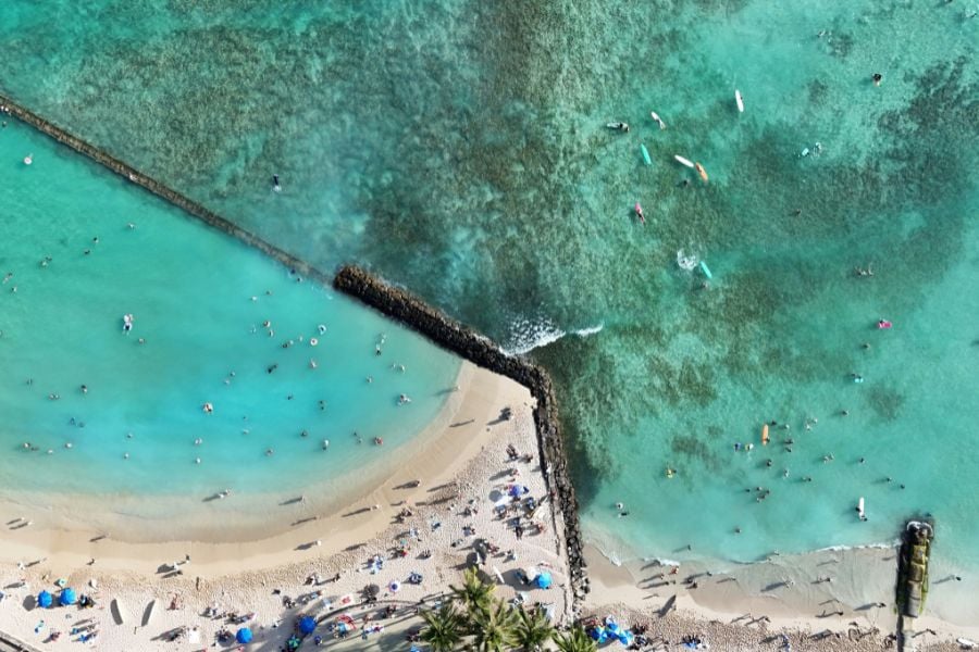 Aerial view of swimmers enjoying turquoise water near a sandy beach.