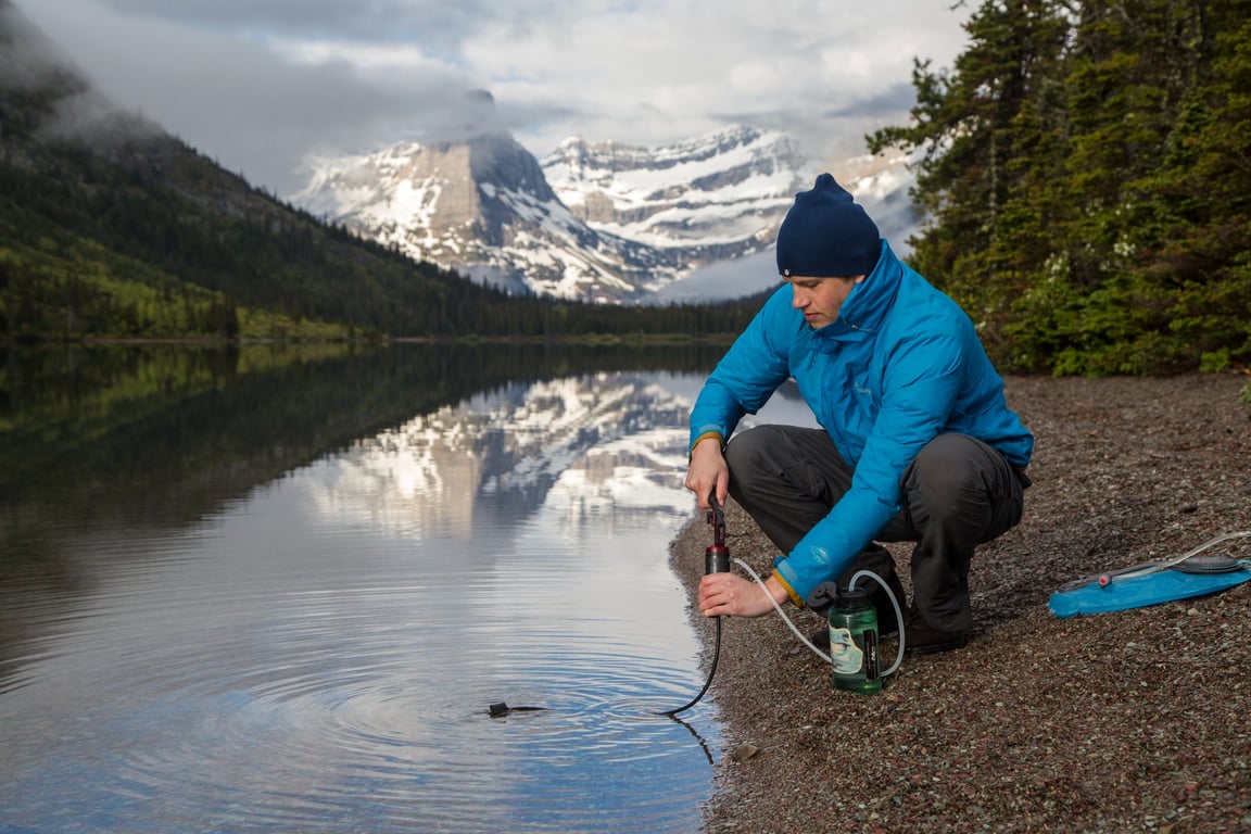 man in blue jacket pumps water to filter from lake